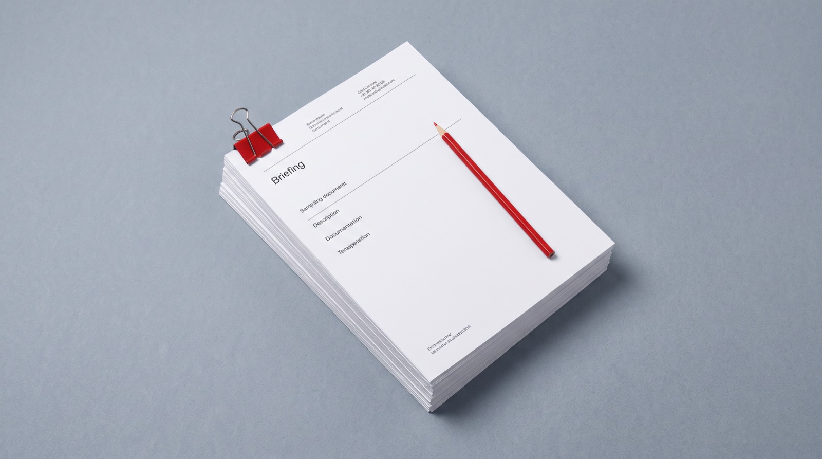A stack of white briefing documents with a red binder clip and red pencil, photographed top-down